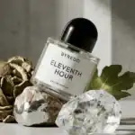 Byredo Eleventh Hour fragrance bottle with decorative rocks and a leaf.
