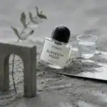 Byredo Eleventh Hour fragrance bottle with a glass of water and minimalist decor.