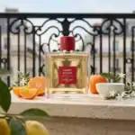 Guerlain Habit Rouge fragrance bottle with oranges and white flowers.