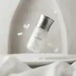 Blanche Bete fragrance bottle with silver cap, floating gracefully with petals.