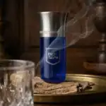 Phantasma Blue perfume bottle with a sleek silver cap and elegant blue glass, emitting a gentle vapo.