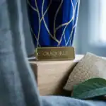 Craquele perfume bottle with gold label and blue design, displayed on a wooden surface.