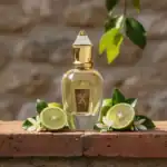 Xerjoff Nio fragrance bottle with gold accents, surrounded by lime slices and white flowers.