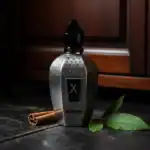 IOMMI luxury perfume bottle with black cap and metallic finish, accompanied by cinnamon stick and gr.