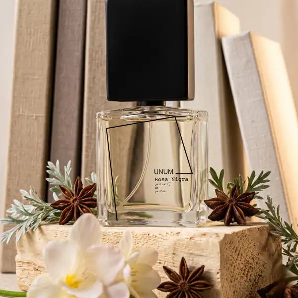 Filippo Sorcinelli Rosa Nigra fragrance bottle with star anise and greenery, displayed on a wooden s.