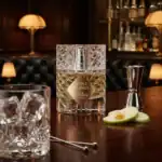 Kilian Apple Brandy fragrance bottle with fresh apple slices and elegant bar setting.