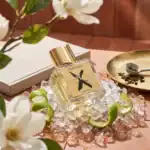 Nishane Wūlóng Chá fragrance bottle with gold cap, displayed on ice with lime peels and tea leaves.