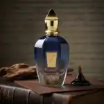 Zero Off fragrance bottle with gold cap, dark blue glass, and a small black perfume droplet on a tex.