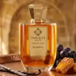 Unique'e Istanbul perfume bottle with elegant gold cap, surrounded by grapes and caramel, highlighti.