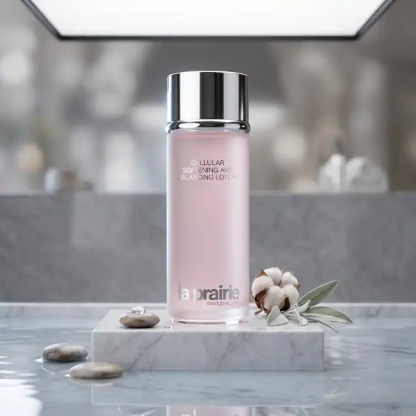Luxurious La Prairie skincare lotion in elegant pink bottle with cotton flowers and stones for a spa.