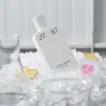 27 87 Elixir de Bombe - A luxurious perfume in minimalist white packaging showcased on ice.