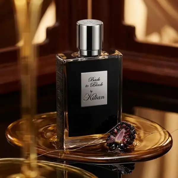 Kilian Back to Black fragrance bottle with blackberries on a gold-toned tray.