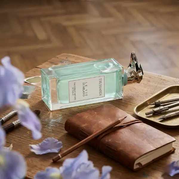 Trussardi Le Essentiel Blumarine perfume bottle on a wooden table with flowers and vintage accessori.