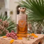 Electimuss Amber Oud fragrance bottle with elegant design, set against a lush green background.