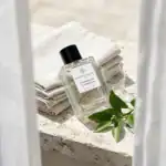 Nobile 1942 Eau Infusion perfume bottle with minimalist design, placed on a stone surface with green.