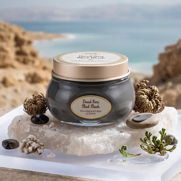 Dead Sea Mud Mask in a glass jar with natural elements, set against a coastal background.