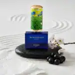 FloraiKu I See the Clouds Go By perfume bottle with artistic design, set on a black stone with cherr.