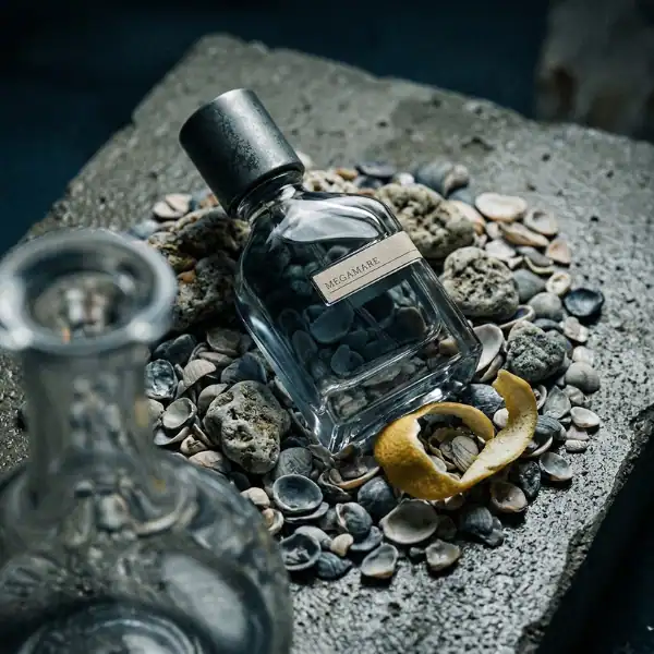 Megmare perfume bottle on pebbles with lemon peel, luxury niche fragrance.
