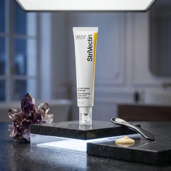 StriVectin eye cream tube on a modern bathroom countertop with a purple crystal and spoon.