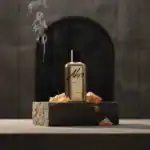 Aho Glow fragrance bottle with incense stick and amber stones on a stone platform.