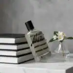 Akro fragrance bottle with minimalist design, placed on a stack of books with a small flower arrange.
