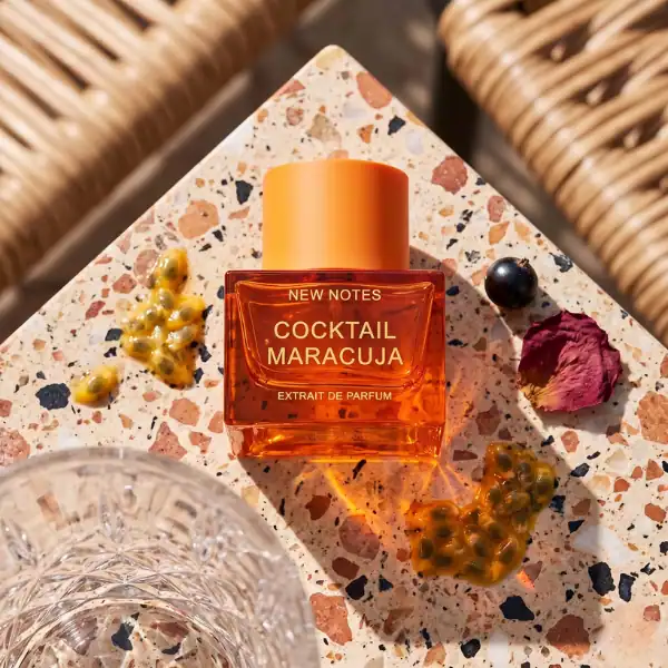 Elegant passion fruit perfume bottle with orange cap on terrazzo surface.
