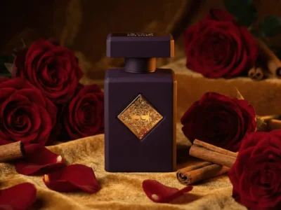 Elegant dark perfume bottle with ornate gold embellishments set against rich red roses and cinnamon, capturing luxury and sophistication.