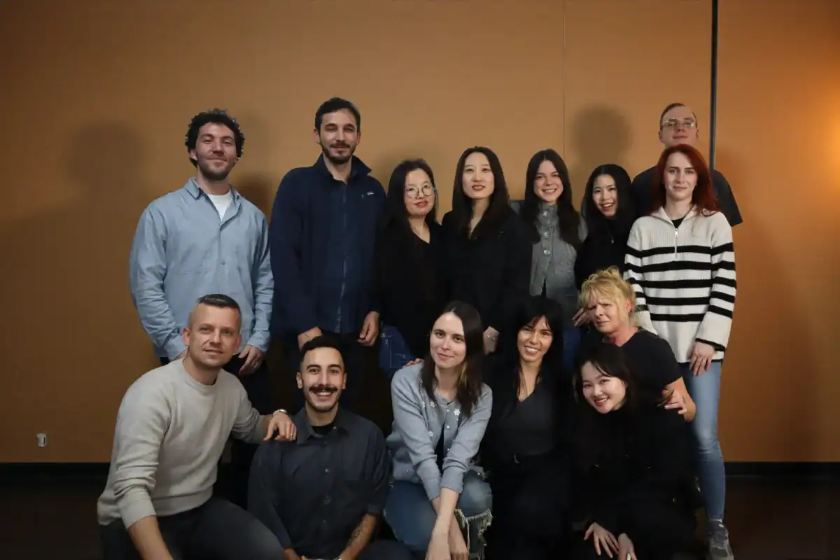 Alwa group photo of diverse team members standing and sitting against a warm-toned background.