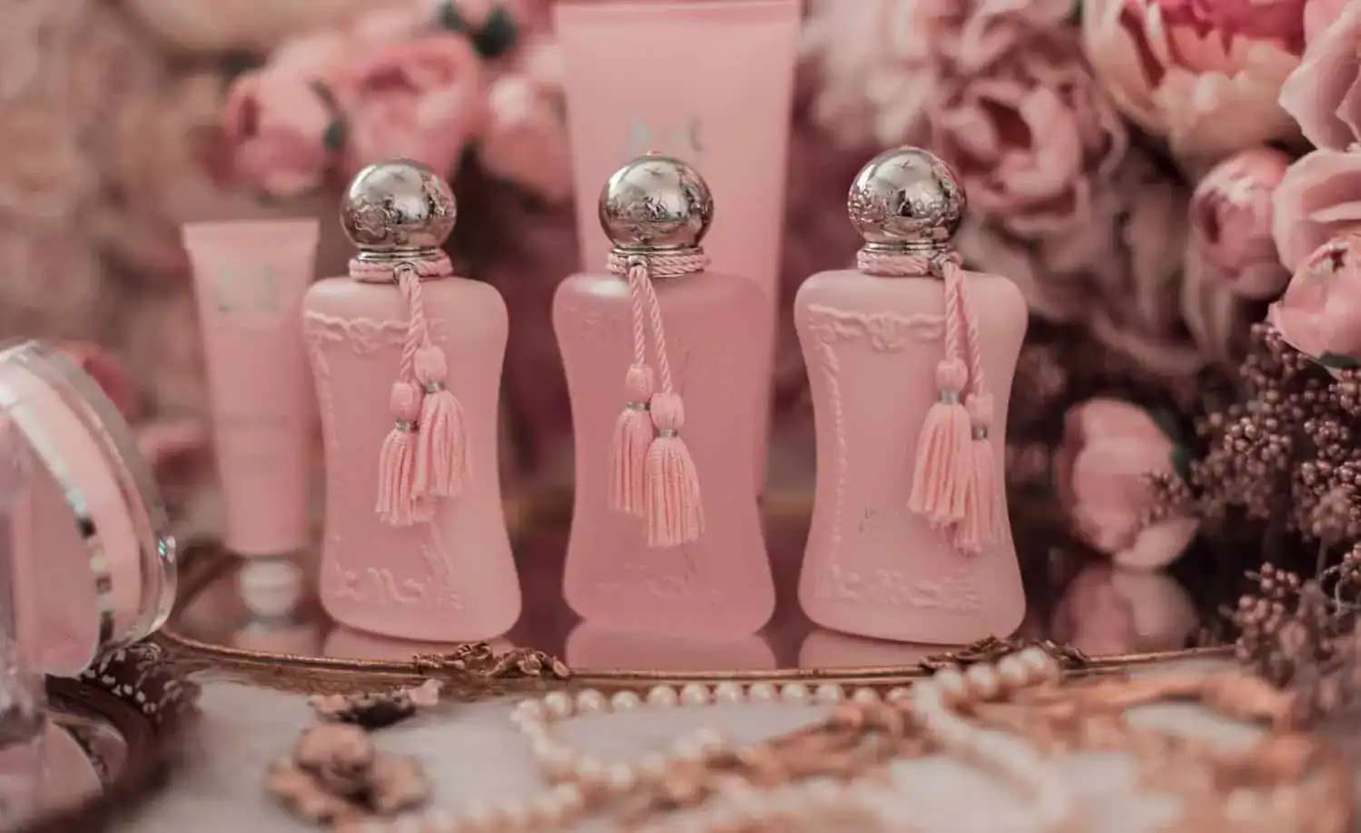 Luxury pink perfume bottles adorned with tassels, set against a backdrop of pink roses and delicate.