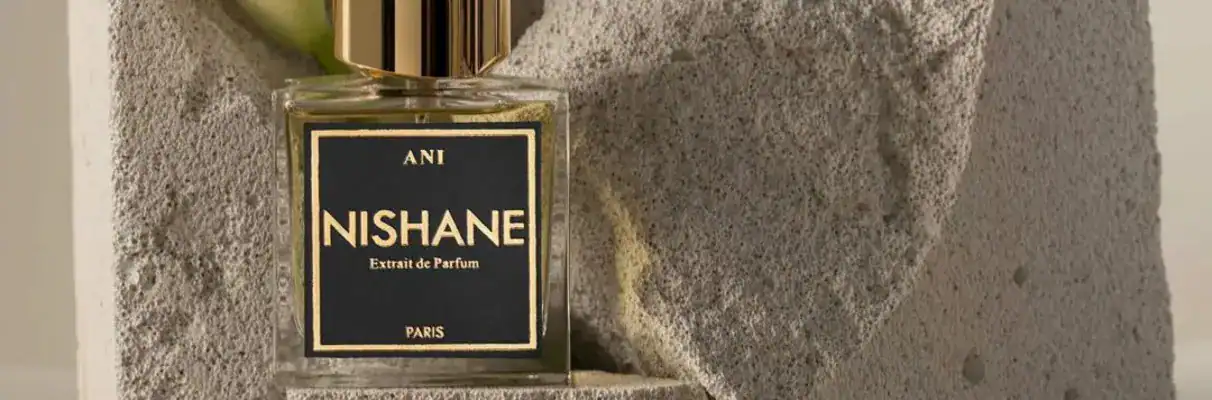 Elegant Nishane perfume bottle with black and gold design on a textured surface.