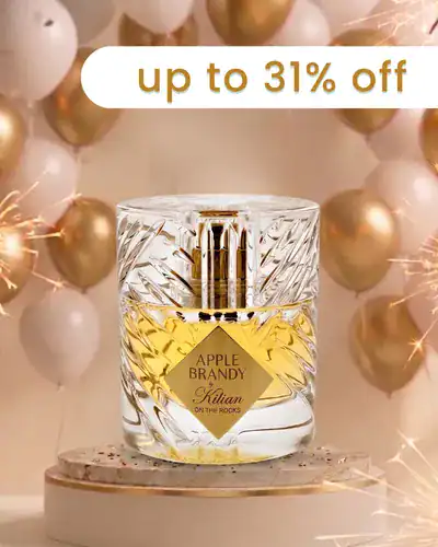 Elegant glass perfume bottle with gold accents and a yellow label, surrounded by festive balloons.