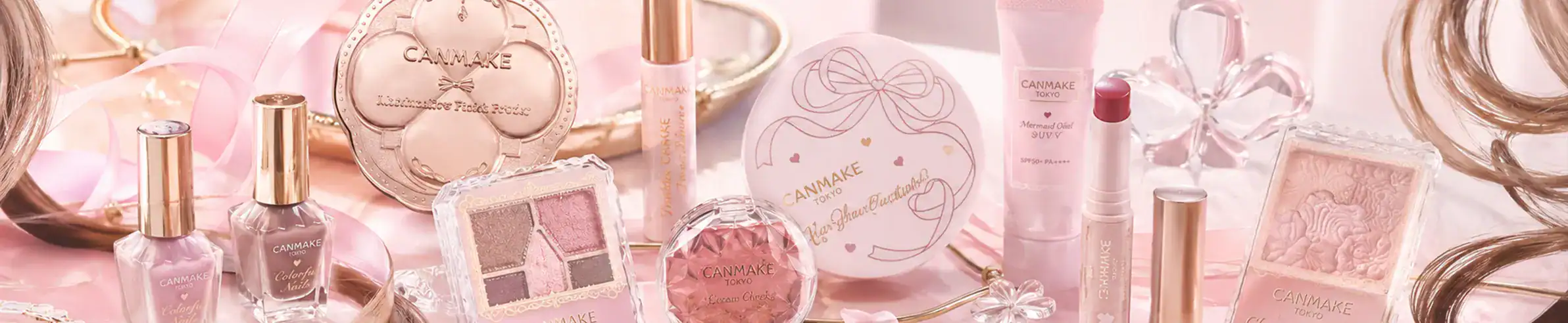 Elegant collection of high-end perfumes, skincare, and hair care products in soft pink tones.