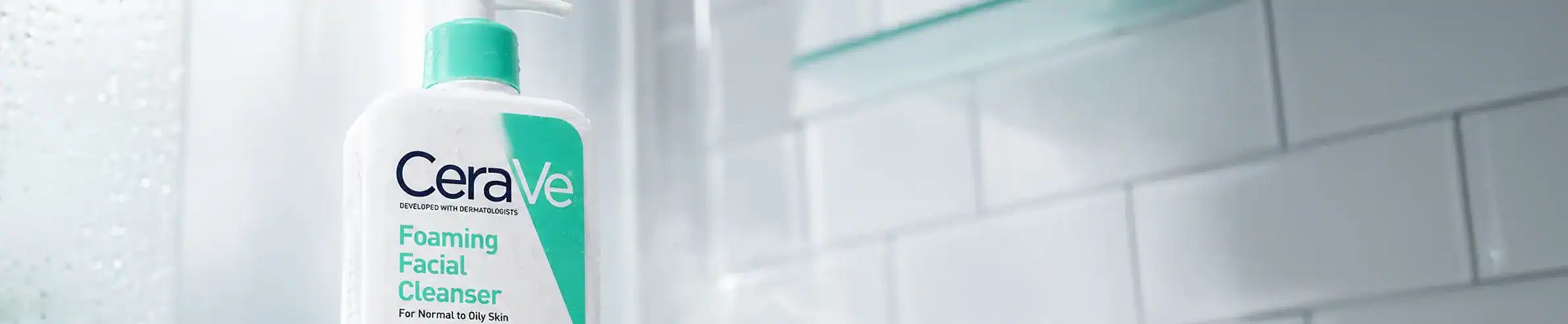CeraVe Foaming Facial Cleanser bottle placed on a bathroom countertop with white tiled wall backgrou.