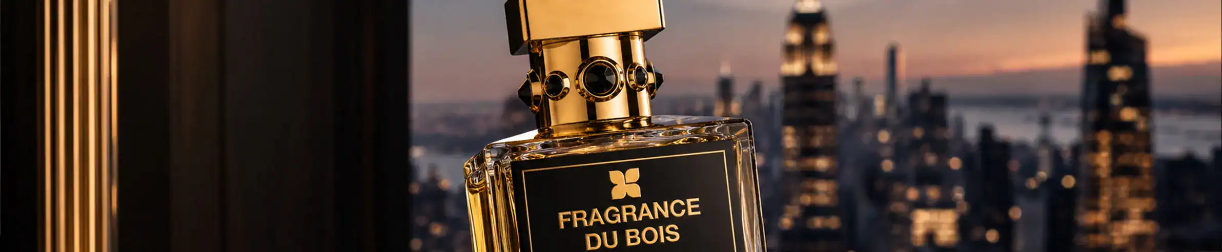 Elegant fragrance bottle with a black and gold design, set against a cityscape at dusk.