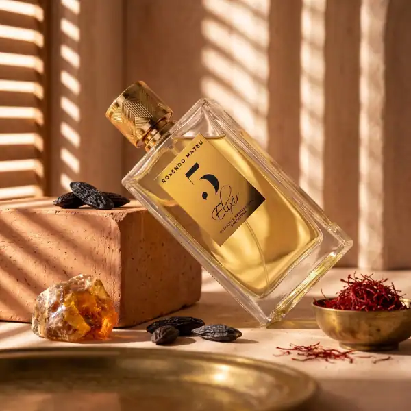 High-end perfume bottle with gold cap, surrounded by spices and natural stones, in warm lighting.