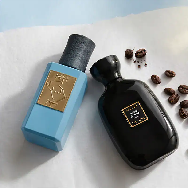 Kawa Kawa and Des Oros luxury perfume bottles with coffee beans.